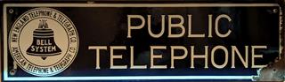 5 1/2" x 19" single sided enameled sign.  

Front left has 1921 Bell system logo, surrounded by NEW ENGLAND TELPHONE & TELEGERAPH CO. / AMERICAN TELEPHONE & TELEGRAPH CO.  

Front Right has PUBLIC / TELEPHONE

Back is white enamel with ping / green paint areas.

All four grommets remain.  Chip by lower left one just barely touches logo.  Right side of sign his chipped up with white border mostly missing.  Bottom right chipped up extends to Ein TELEPHONE.  Chip on top blue border above / left of "T".  Back chipping less severe than front, with most on the bottom right back.